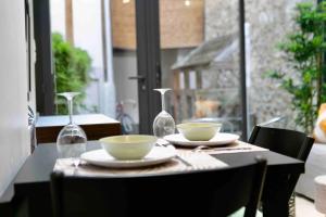 a table with two bowls and two wine glasses at New Hypercenter Appart'Hôtel Sweet Green in Fontainebleau