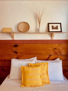 a bed with white pillows and a wooden headboard at Pousada Ziriguidüm in Caraíva