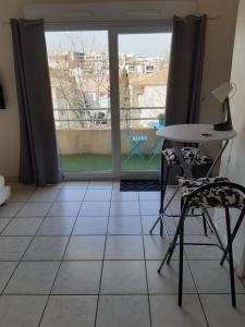 Zimmer mit einem Tisch, Stühlen und einem Fenster in der Unterkunft Studio dans résidence avec piscine in Montpellier