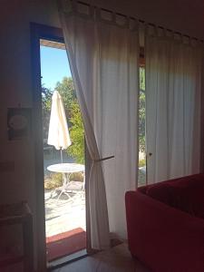 an open door to a patio with a table and umbrella at Il Poggio in Murlo +2 photos