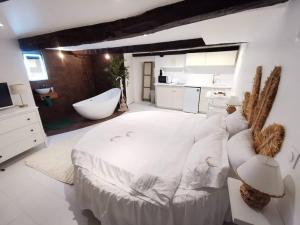 a white bedroom with a tub and a large bed at Studio équipé avec Lit rond / baignoire ilot / Table massage Aux Arcs in Les Arcs sur Argens