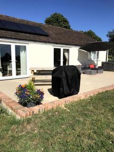 a house with a patio with a bench and umbrella at Lovely two bedroom bungalow with hot tub in Yeovil
