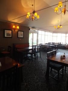 ein Esszimmer mit Tischen, Stühlen und Fenstern in der Unterkunft The Red Lion, Stretham in Ely