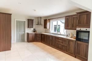 a large kitchen with wooden cabinets and a window at Maple Grove, Fahan in Fahan