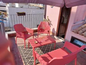 シラクーサにあるラ コロンバイア ディ オルティージャのパティオ(赤い椅子、テーブル、パラソル付)