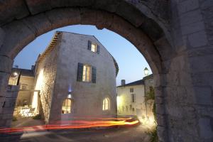 an archway in a building with a car driving past it at Design Hôtel des Francs Garçons in Saint-Sauvant