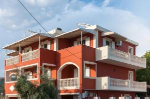 un edificio rosso con balconi bianchi di Avyssos Residents a Kalamákion