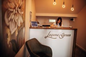 a woman sitting at a counter in a room at Laguna Green Guest House in Niš