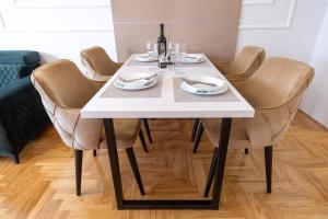 a white table with chairs and wine glasses on it at Apartman Vanilla Sky in Trebinje