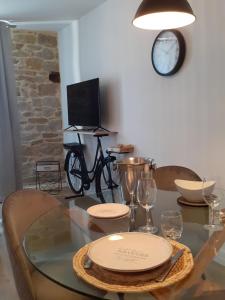 uma sala de jantar com uma mesa de vidro e um relógio em L' atelier du 26 em Dinan