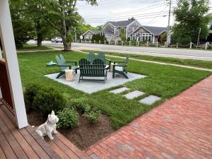 a dog sitting on a porch next to a picnic table and benches at The Franklin Hotel Martha's Vineyard in Edgartown