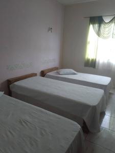 three beds in a room with a window at POUSADA GRACAS in Cachoeira Paulista