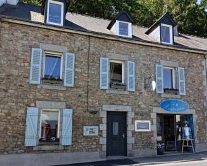 un edificio de ladrillo con ventanas con persianas azules y una puerta en Les chambres de l'Atelier, en Pont-Aven