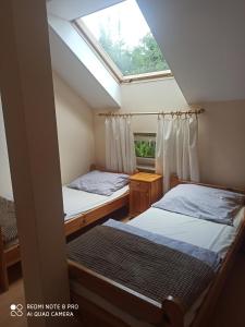 two beds in a small room with a window at Zielony Zakątek nad Jeziorem in Danowskie