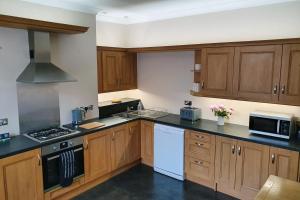 a kitchen with wooden cabinets and white appliances at Coastal escape in the heart of Saltburn in Saltburn-by-the-Sea