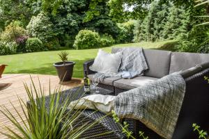a couch sitting on a patio in a garden at Lower Trengale Farm Holiday Cottages in Liskeard