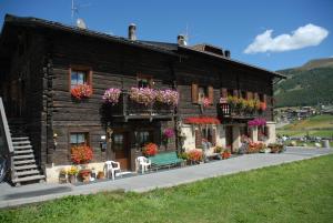 a building with flowers and a bench in front of it at Bait da Marieta in Livigno