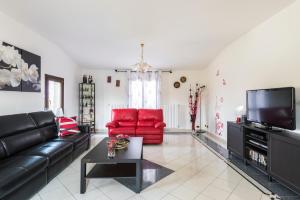 a living room with a black leather couch and red chairs at Casa delle Noci country house, pool & SPA in Modena
