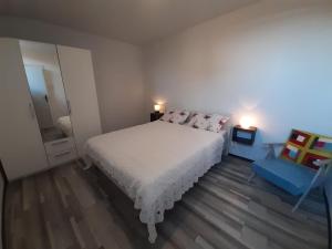 a bedroom with a white bed and a blue chair at Apartman Burte, Komiža in Komiža