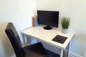 a computer monitor sitting on a desk with a chair at Coastal escape in the heart of Saltburn in Saltburn-by-the-Sea