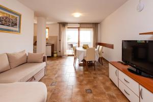 a living room with a couch and a tv and a table at Apartments Smiljanic in Tribunj