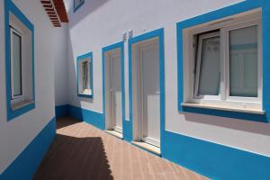 a building with blue and white walls and windows at Sudoeste Guest House in Odeceixe
