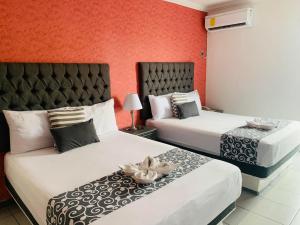 two beds in a hotel room with red walls at Hotel & Suites Bausan in Boca del Río