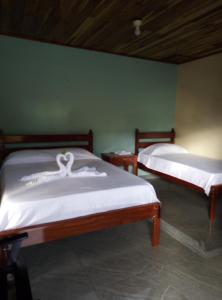 2 camas con sábanas blancas en una habitación en Cabinas El Pilón Río Celeste en San Rafael