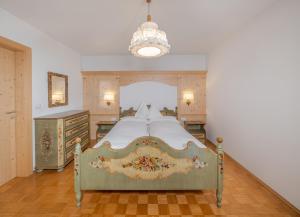 - une chambre avec un grand lit et un lustre dans l'établissement Gabriel, à Ortisei