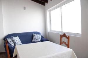 a blue couch with a table and a window at Sudoeste Guest House in Odeceixe