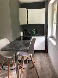 a kitchen with a table and two white chairs at Apartament KOMPAS in Świeradów-Zdrój