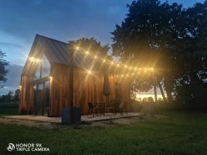 a cabin with a table and chairs under a string of lights at Mazurskie Stodoły in Piecki