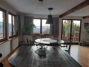 uma sala de jantar com mesa, cadeiras e janelas em Dom Przy Lesie em Wisla