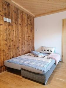 a bed in a room with a wooden wall at Ferienwohnung Bauer in Böbing