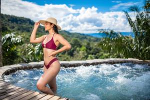 a woman in a hat standing in a swimming pool at Finca Heimatlos in Puyo