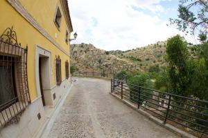 une rue vide avec un bâtiment et une montagne dans l'établissement Apartamento familiar en Toledo, con 2 dormitorios, camas de matrimonio, ideal ubicación y fantàsticas vistas, à Tolède