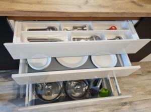 an open kitchen drawer with dishes and utensils at Apple Apartments - Gdańska PRYWATNE MIEJSCE PARKINGOWE in Łódź