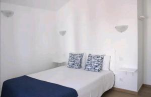a white room with a bed with two pillows on it at Sudoeste Guest House in Odeceixe