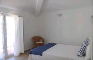 a bedroom with a bed and a window and a chair at Sudoeste Guest House in Odeceixe