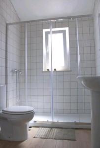 a bathroom with a toilet and a window and a sink at Sudoeste Guest House in Odeceixe