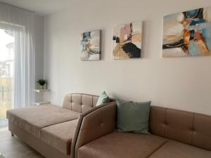 un sofá en una sala de estar con pinturas en la pared en ROYAL AQUAMARINE - lakeside luxury flat at Balaton, en Keszthely