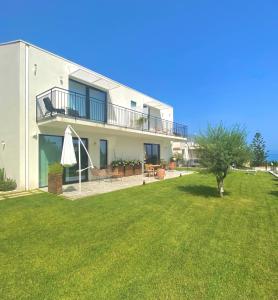 une maison avec une pelouse verte devant elle dans l'établissement Nacàri Home, à Giardini Naxos