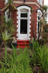 a red brick house with a white window and plants at The Parks in Torquay