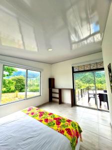 a bedroom with a large bed and large windows at Villa Tokyo in Ibagué