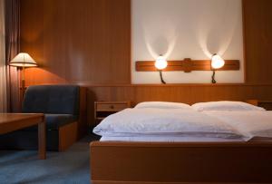 a bedroom with a bed and a chair and lights at Hotel Ungarische Krone in Bruckneudorf