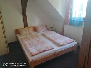 uma cama com cobertores e almofadas cor-de-rosa e brancos em Penzion U Hladů em Úlice