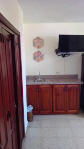 uma cozinha com um lavatório e uma televisão na parede em D9 Casa de Huespedes em Santo Domingo