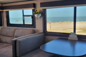 a room with a couch and a table and two windows at Brand New RV Bay Front in Port Lavaca