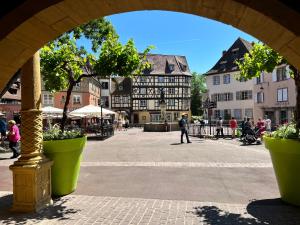 een boog in een stad met mensen die lopen en gebouwen bij Le Schdorky in Colmar