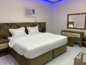 a bedroom with a large bed and a mirror at أجنحة عبدالعزيز للوحدات السكنية in Sulţānah